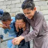 Schoolchildren using water pump during recess