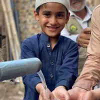 Children washing hands at a water pump